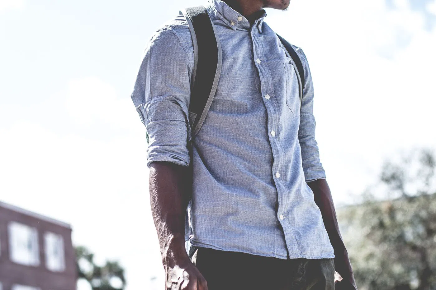 The linen shirt in indigo, worn open over a bag strap.