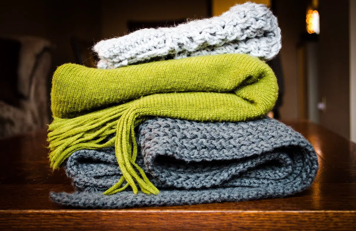 Wool blankets folded in a stack, moss on top of slate.