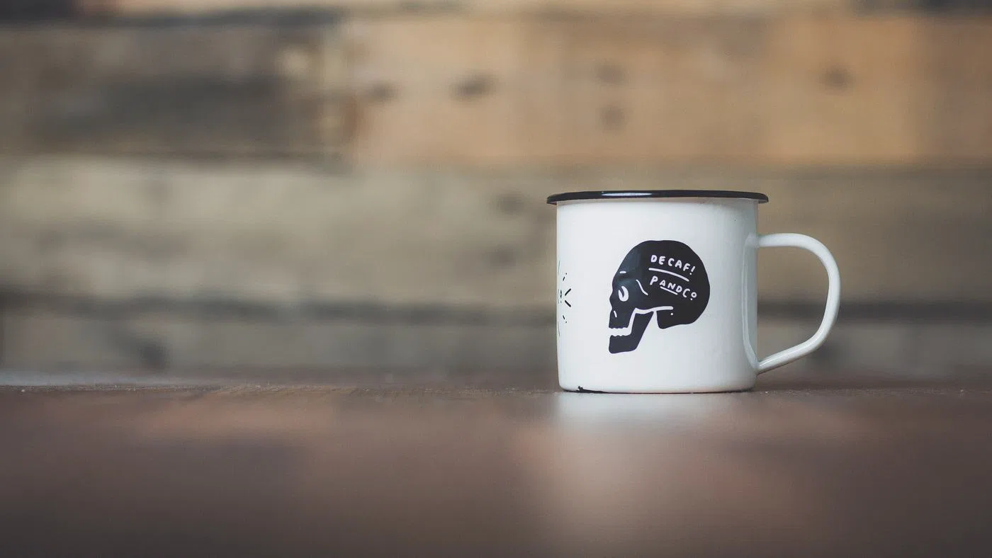 A cream enamel mug on a scrubbed wooden table.
