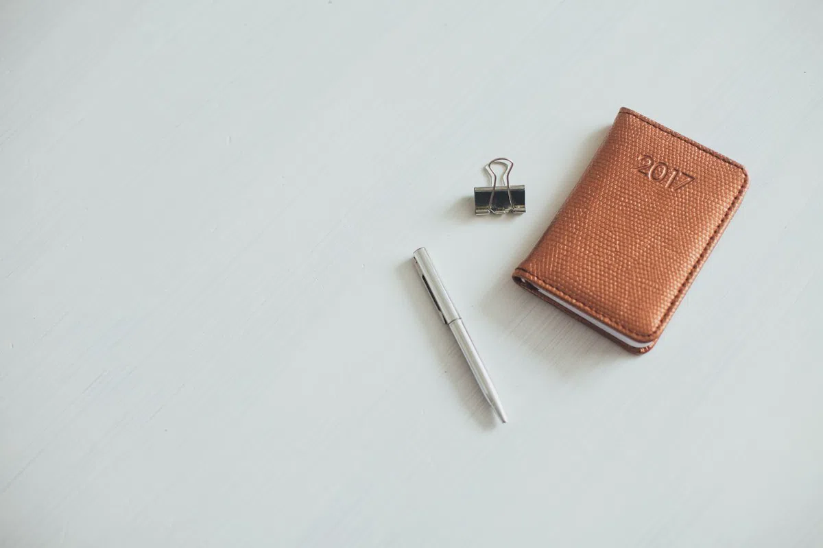 The pocket leather notebook, closed, beside a pencil.