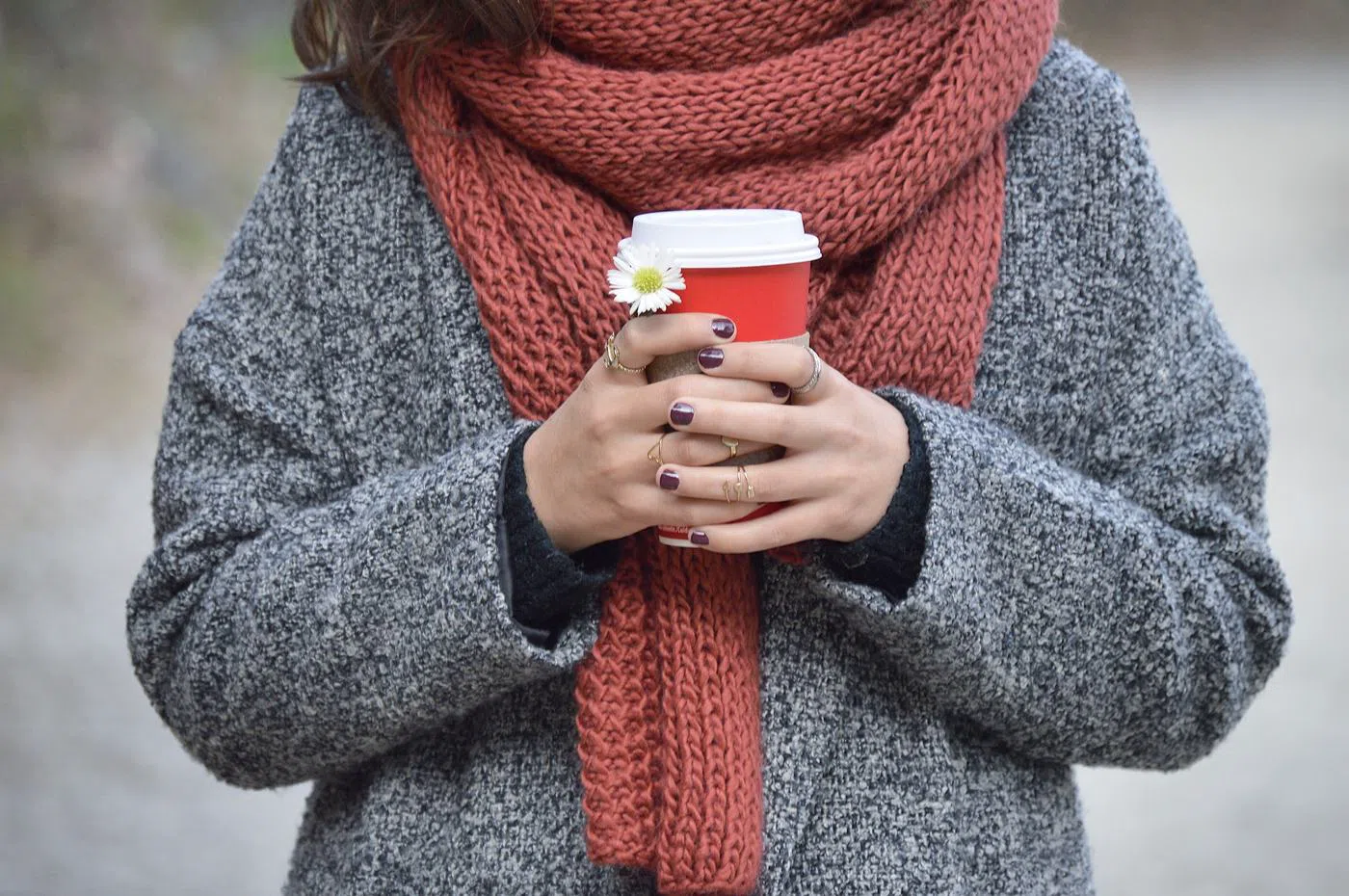 The wool scarf in rust, worn over a grey coat.