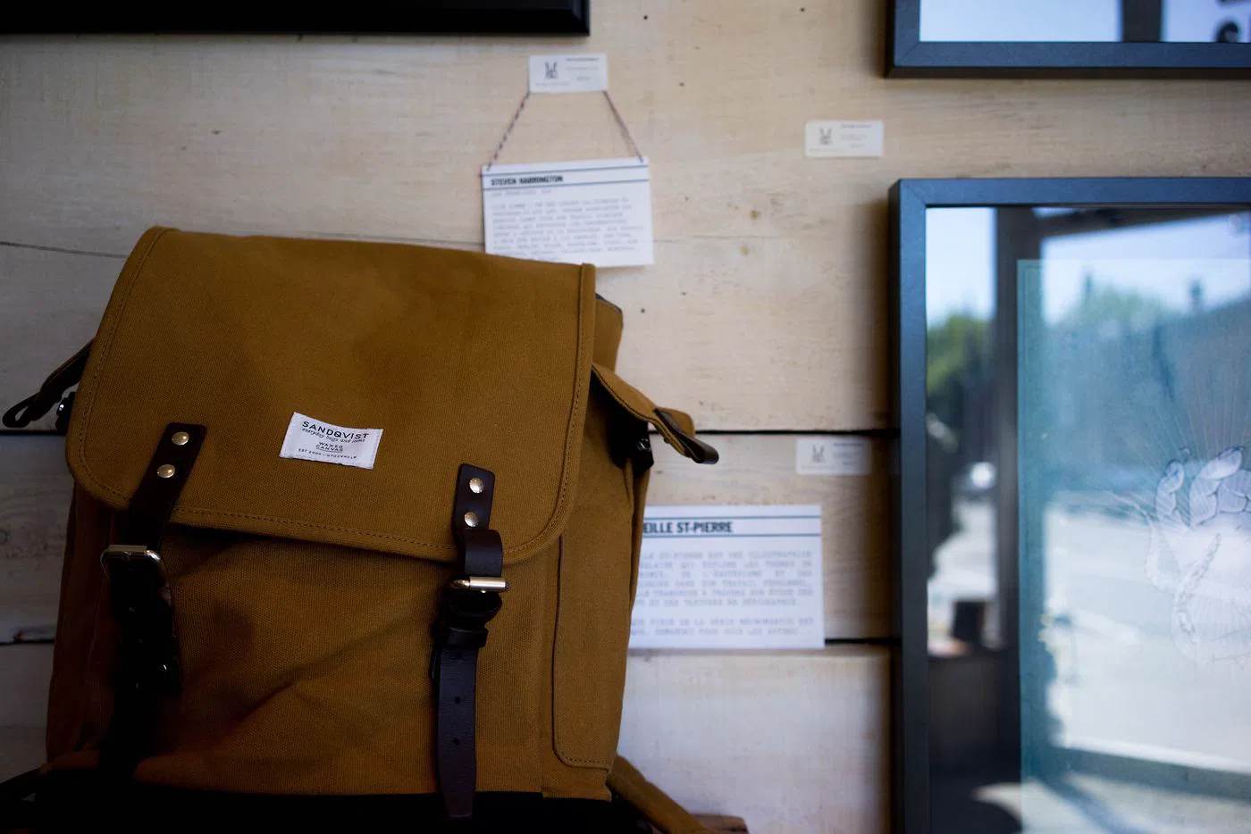 The canvas backpack in tan, buckled shut.